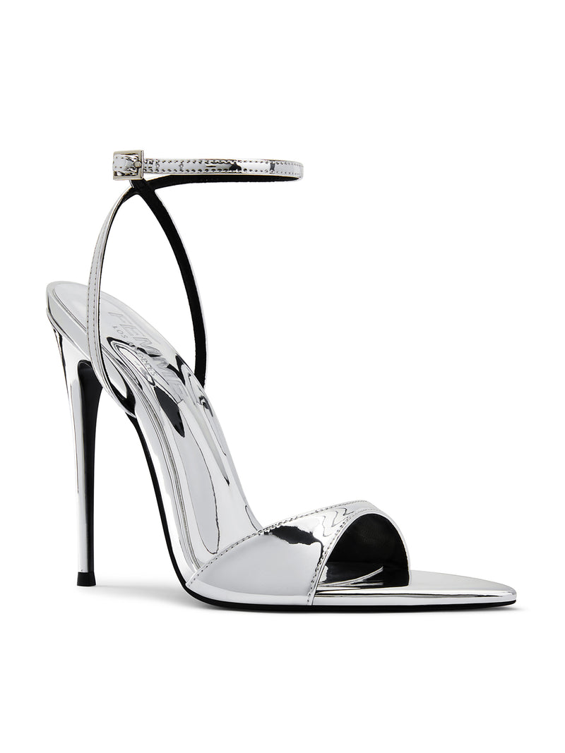 FEMME LA GG Heel in mirror silver, 3/4 back angle showing ankle strap, gold buckle, and reflective silver insole