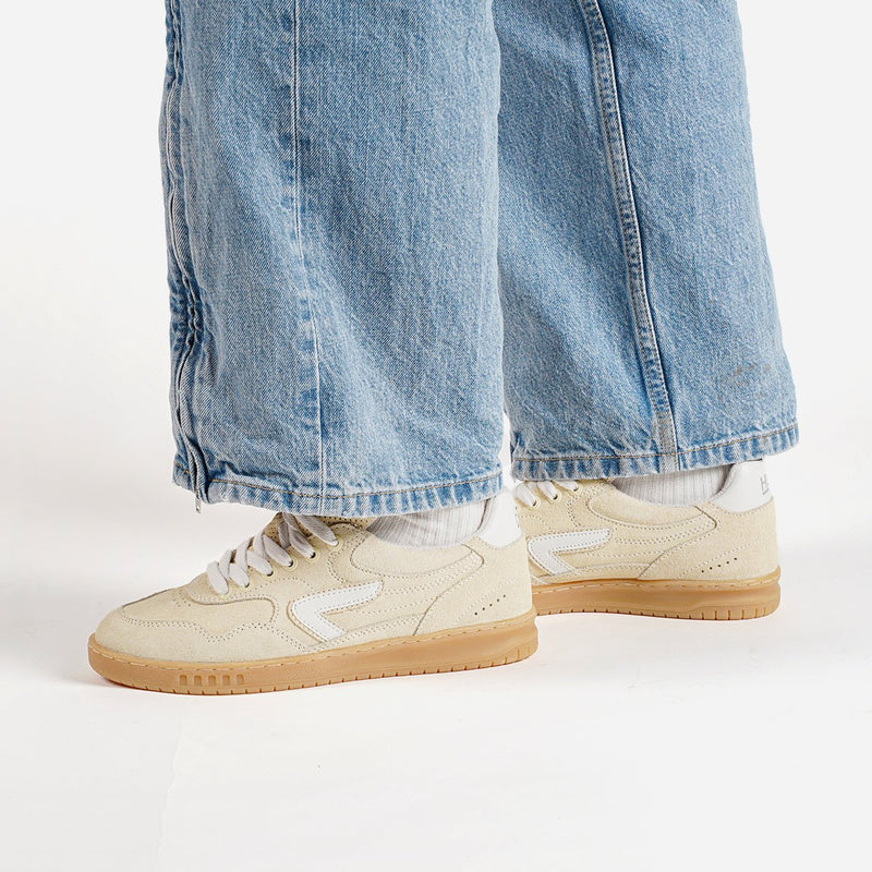 Butter yellow HUB sneakers with white laces worn with light blue jeans on a white background